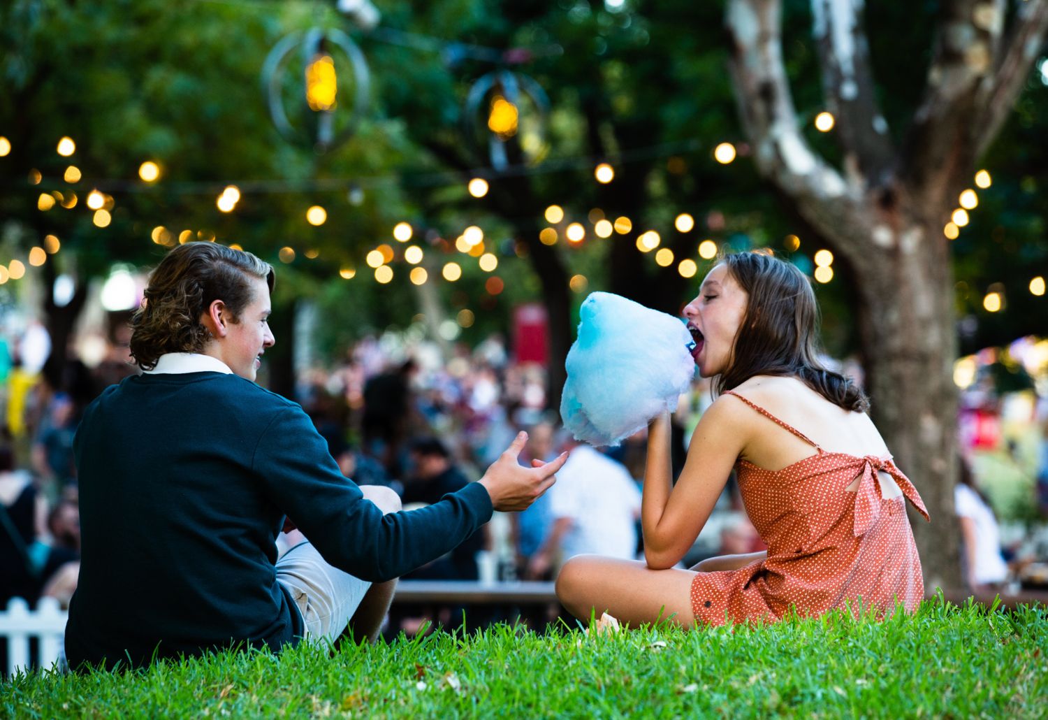 Two young teenagers share blue fairyfloss